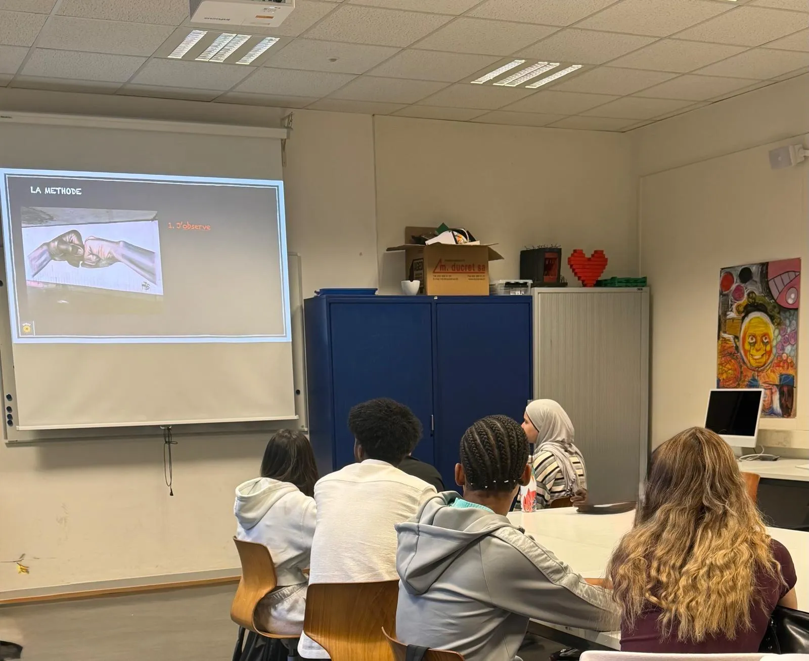 Élèves attentifs pendant un atelier WHAT en classe, une diapositive projetée au mur